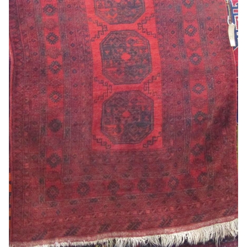 2399 - Bokhara type rug with geometric medallion decoration upon a deep red ground, 190 x 130cm