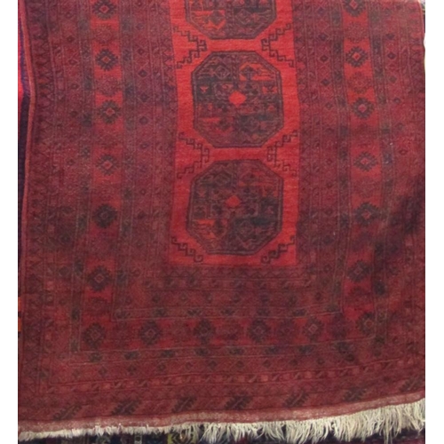 2399 - Bokhara type rug with geometric medallion decoration upon a deep red ground, 190 x 130cm