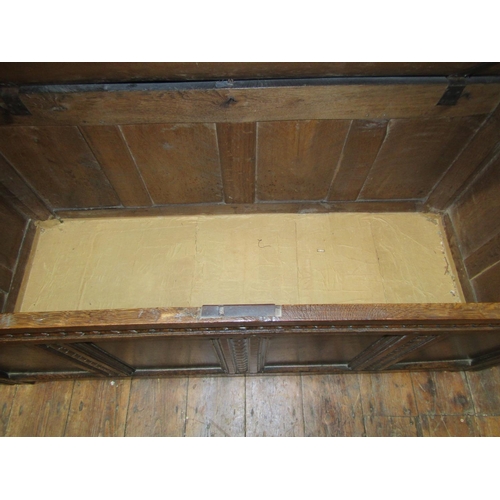 2077 - An 18th century oak coffer with hinged lid over a moulded panelled frame with repeating carved detai... 