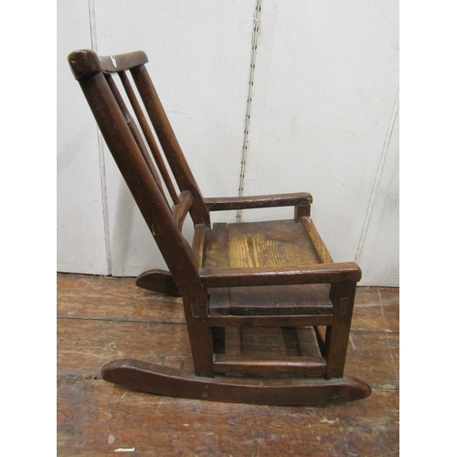 2142 - An 18th century primitive child's rocking chair, principally in oak with simple stick-back