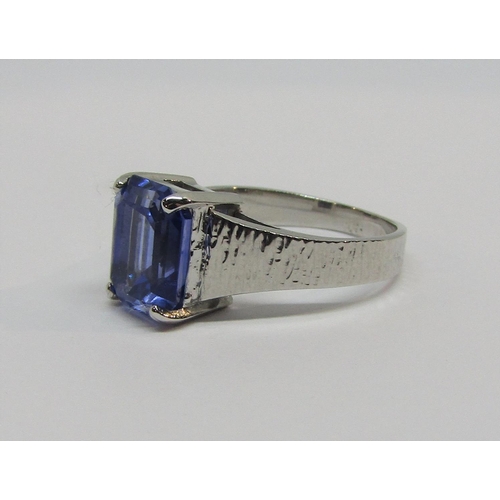 919 - 18ct white gold emerald-cut sapphire ring with textured shank, 8.5 x 6.5mm approx, size I/J, 4g