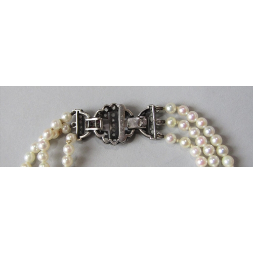 931 - Triple strand cultured pearl bracelet, the associated Art Deco white metal clasp set with rose cut d... 