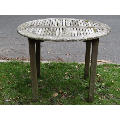 2052 - A weathered teak garden table of circular form with segmented slatted top on square cut supports tog... 