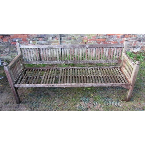 2038 - A weathered teak garden bench with slatted back and arms beneath faceted finials (AF), 6ft long