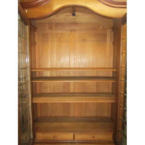 2415 - A substantial walnut bookcase with arched outline enclosed by two glazed and barred doors, the glass... 