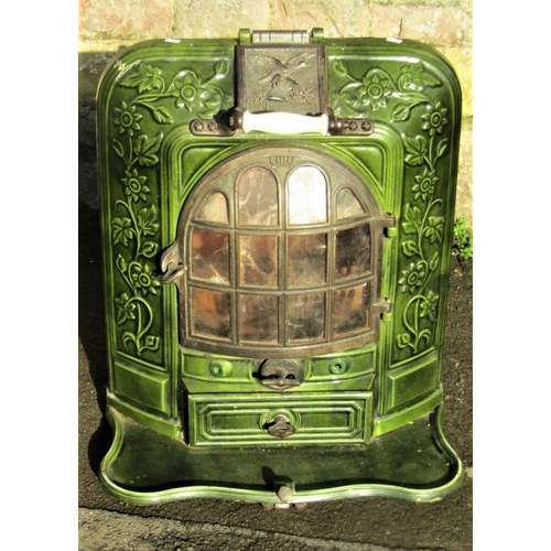 2108 - A French cast iron and green enamel stove enclosed by a bow fronted arched panelled door within a de... 