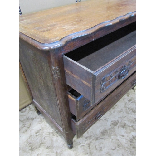 2284 - An antique oak commode of three long drawers with carved foliate detail over a shaped apron and squa... 