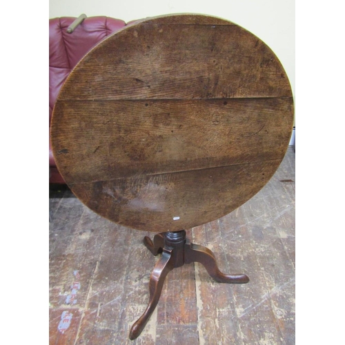 2655 - A Georgian oak snap top table the circular top 80 cm in diameter, raised on a turned pillar and shap... 