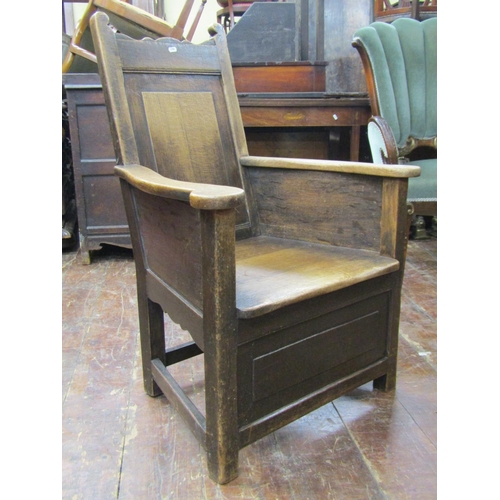 2664 - An 18th century oak enclosed chair with rectangular panelled back beneath shaped cresting rail, with... 