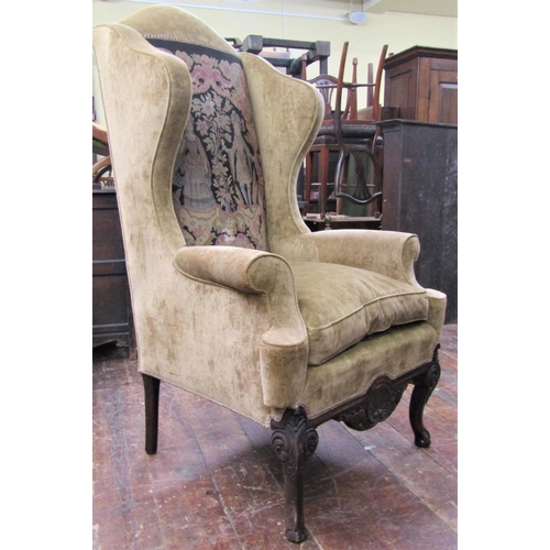 2676 - A substantial Georgian style wing chair with scrolled arms raised on a carved frame, cabriole forele... 