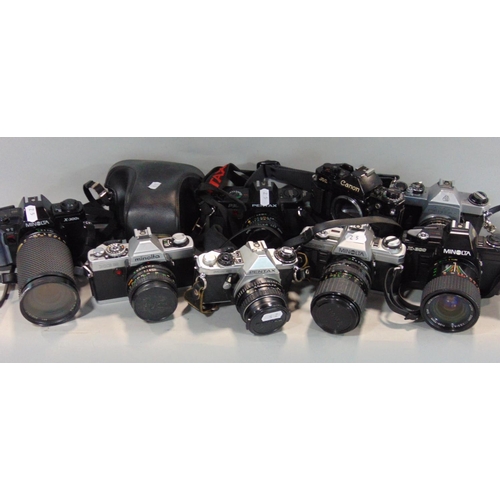 565 - Box of manual 35mm SLR cameras to include Minolta, Pentax and Canon, most with prime and zoom lenses