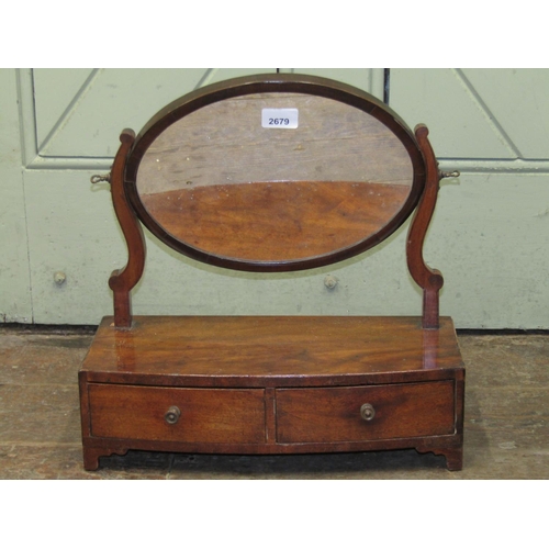 2679 - A simple Georgian mahogany toilet mirror, the oval mirror plate raised on a bow fronted base incorpo... 