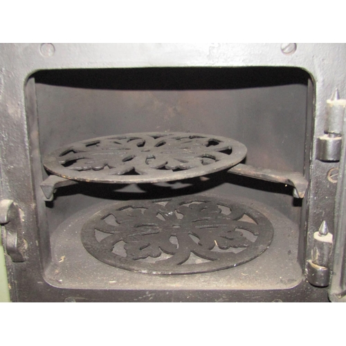 2103 - A small 19th century cast iron range partially enclosed by a single oven door with decorative expose... 