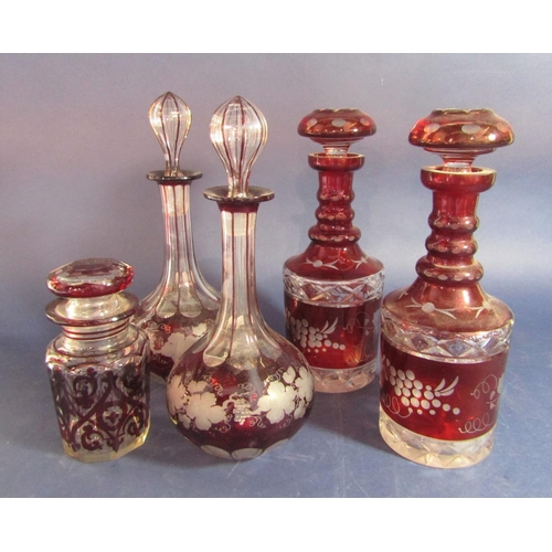 1152 - A collection of cranberry cameo type glassware comprising pair of decanters with leaf and berry etch... 