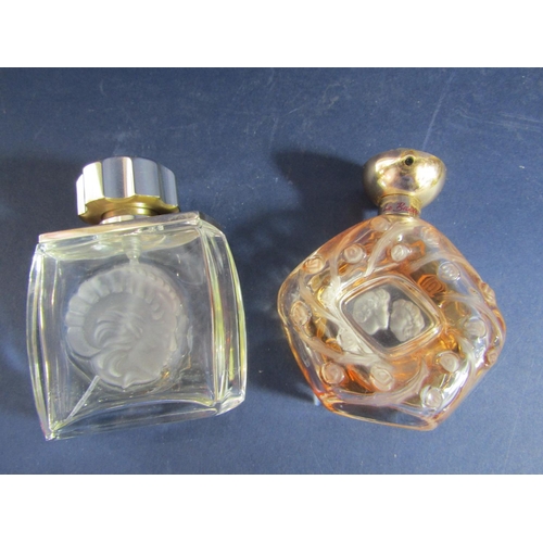 1181 - Two Lalique perfume bottles, one decorated with flower head decoration with a central design of two ... 