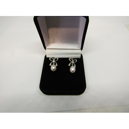 1395 - Pair of antique style 9ct white gold pearl drop earrings with diamond set bow surmounts,  2.6g