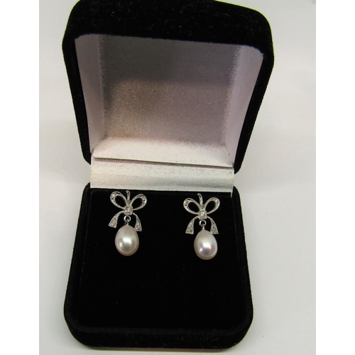 1395 - Pair of antique style 9ct white gold pearl drop earrings with diamond set bow surmounts,  2.6g