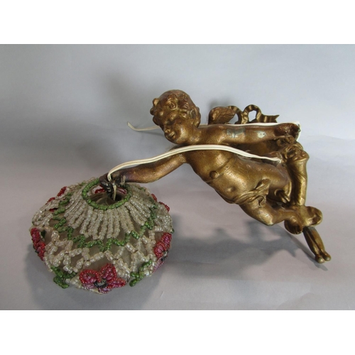 1603 - Cast gilt metal figural lamp in the form of a cherub holding a beaded shade decorated with flowers, ... 