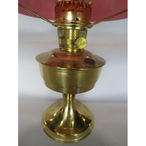 1604 - Aladdin brass oil lamp with red shade and flue, 60cm high total