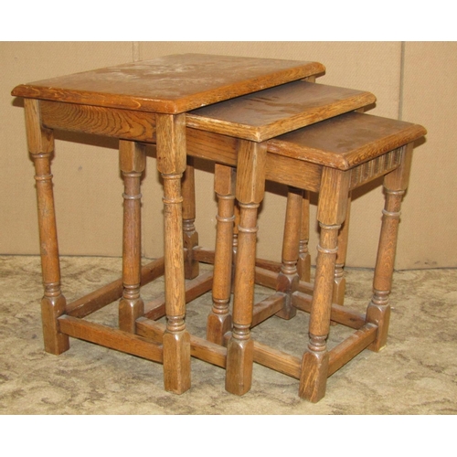 2175 - A nest of three graduated oak Old English style occasional tables, raised on turned gun barrel suppo... 