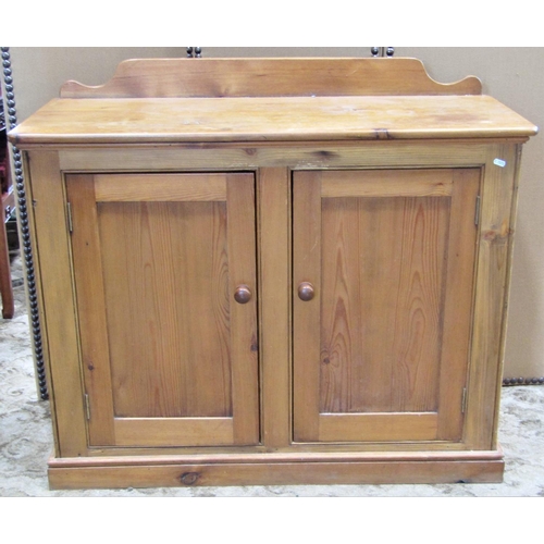 2189 - A stripped pine side cupboard enclosed by a pair of rectangular panelled doors, set on a shallow mou... 