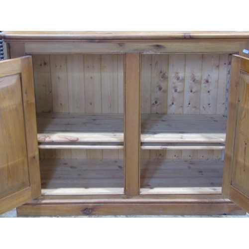 2189 - A stripped pine side cupboard enclosed by a pair of rectangular panelled doors, set on a shallow mou... 