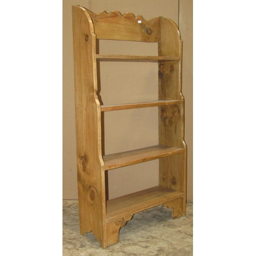 2203 - A small stripped and waxed pine freestanding waterfall type bookcase with fixed shelves and shaped o... 