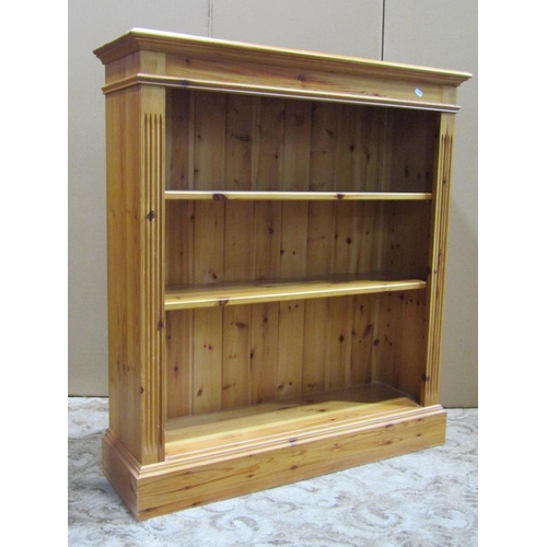 2203 - A small stripped and waxed pine freestanding waterfall type bookcase with fixed shelves and shaped o... 