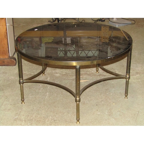 2233 - A low circular occasional table with inset smoked glass top, raised on a cast brass effect metal bas... 