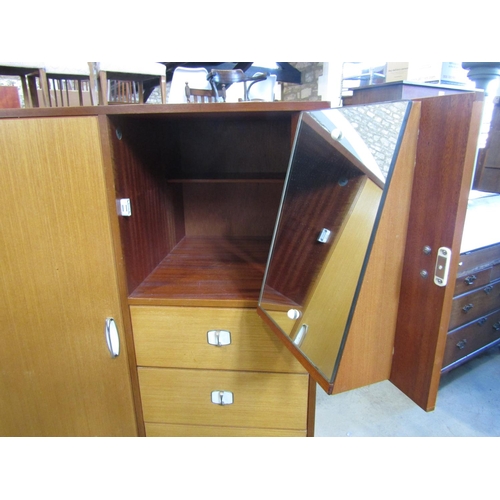 2263 - A small teak combination wardrobe enclosed by an arrangement of two doors and tower of six drawers, ... 