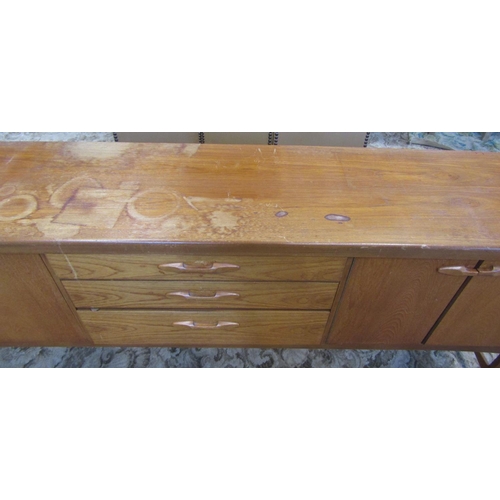 2297 - A long and low retro teak sideboard enclosed by an arrangement of three doors one with fall front fl... 