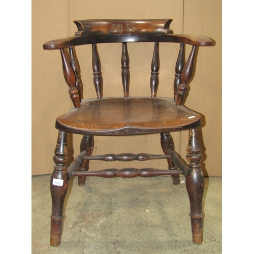 2329 - A 19th century elm and beechwood smokers bow elbow chair with turned spindle back over a saddle shap... 