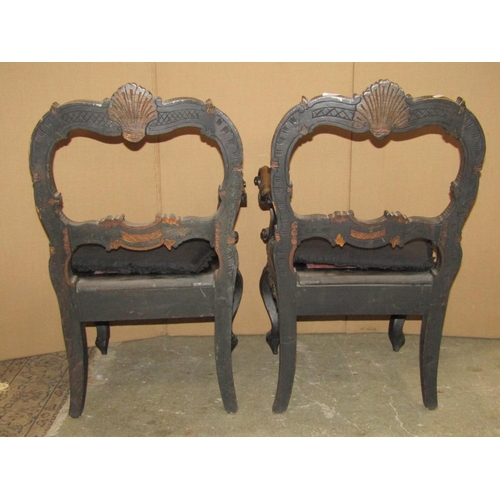 2382 - An unusual pair of low Victorian chairs with ebonised carved and scrolling moulded gilt highlighted ... 