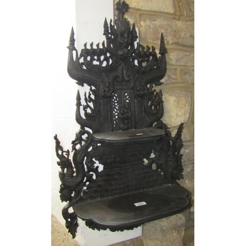 2383 - An antique Indonesian graduated two tier wall shelf with profusely carved scrolling dragon, bird, de... 