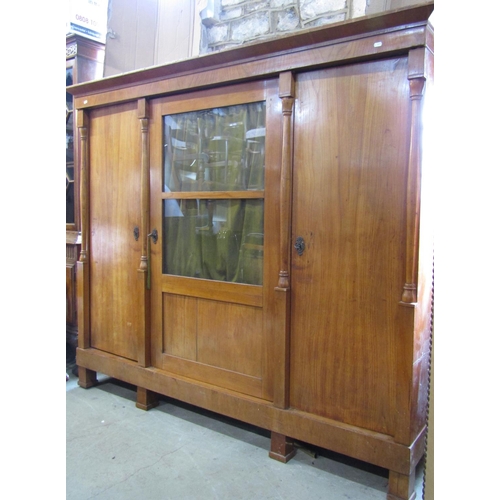 2344 - A 19th century continental fruitwood side cupboard enclosed by three full length doors, the central ... 