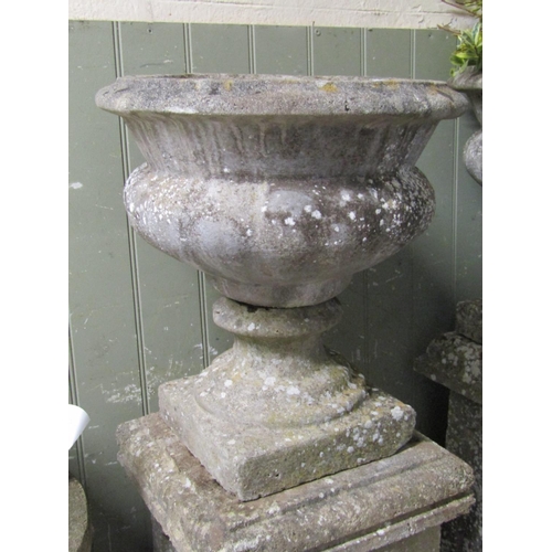 2065 - A pair of reclaimed garden urns of circular tapered and lobbed form with stepped sockles raised on s... 