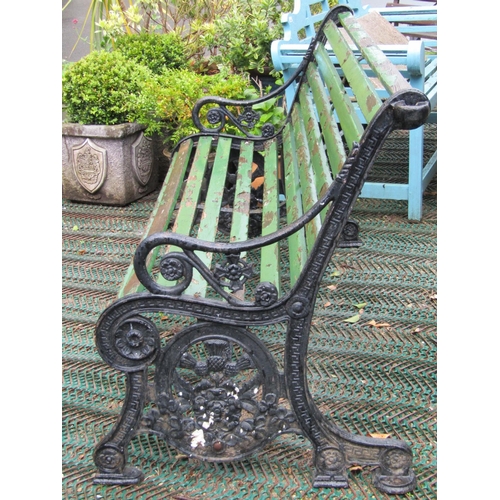 2120 - A Victorian three seat garden/park bench with weathered green painted timber lathes raised on a pair... 