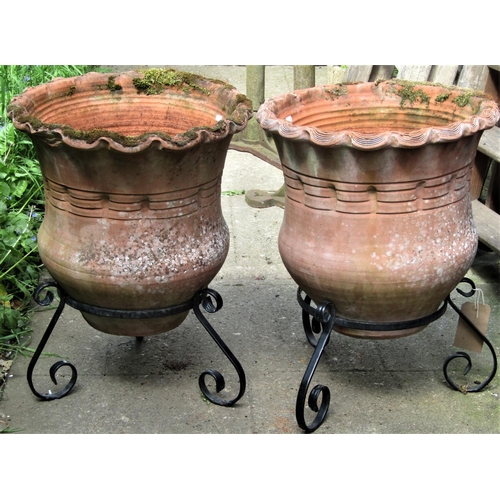 2071 - A pair of weathered terracotta planters, with crimped rims and circular bodies, raised on associated... 