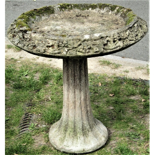 2122 - A reclaimed two sectional bird bath of circular form with fruiting vine lip and raised on a fluted p... 