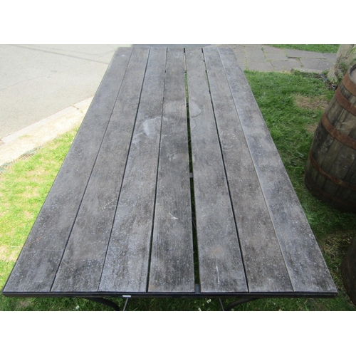 2144 - A garden table with inset weathered wooden planked top, raised on a heavy scrolled ironwork base, 20... 