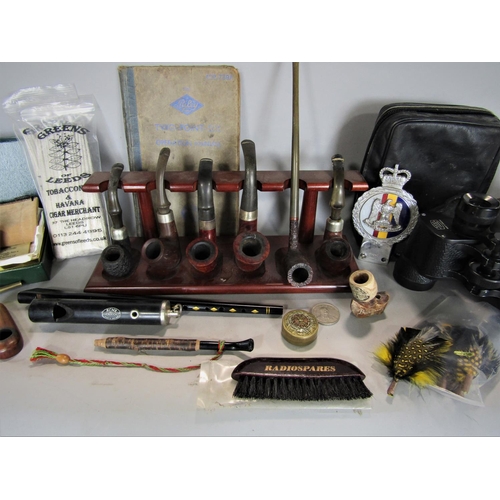 700 - A box of miscellaneous items to include a collection of pipes, binoculars, pin badges, etc