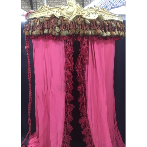 1619 - Bed canopy (width 65cm) with attached long red voile type curtains adorned with tassels and with tie... 