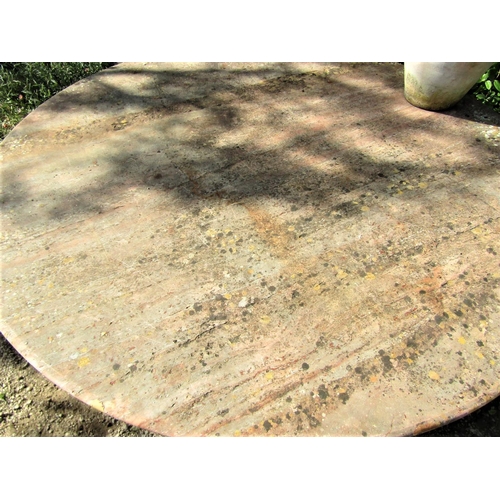 79 - A circular garden table with weathered marble finish, the 120cm diameter top raised on three column ... 