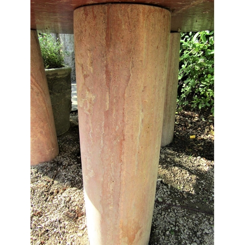 79 - A circular garden table with weathered marble finish, the 120cm diameter top raised on three column ... 