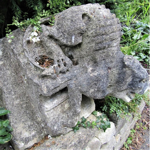 84 - An early limestone carving of a fabulous beast in angry downward pose, 70cm high, overall depth appr... 