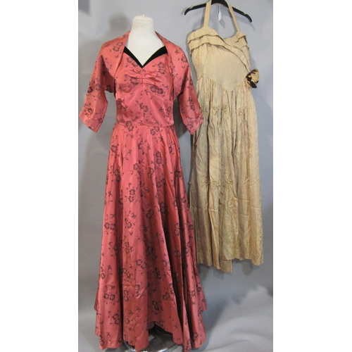 482 - 2 tailored vintage evening dresses. First is in patterned salmon satin trimmed with black velvet, wi... 