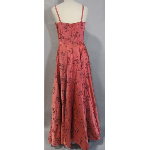 482 - 2 tailored vintage evening dresses. First is in patterned salmon satin trimmed with black velvet, wi... 