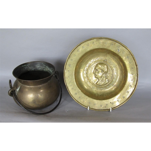 565 - A bronze cauldron with loop handle and a further embossed brass dish with hammered and stamped detai... 