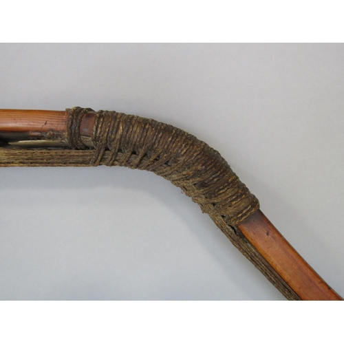 622 - An antique inuit bow in cedar wood, with additonal hide and plaited cord detail, 123 cm in length