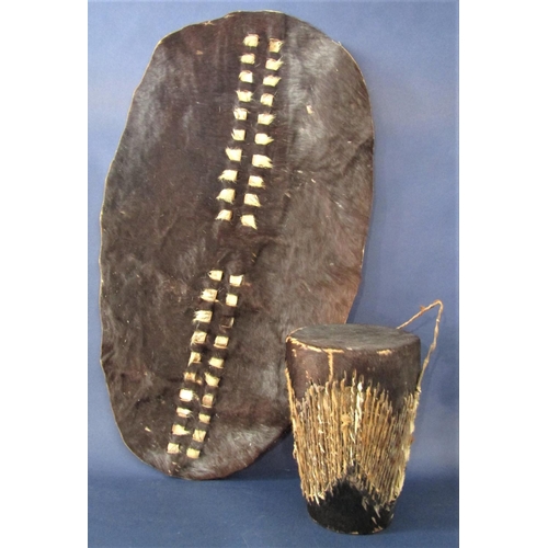 545 - Tribal interest - hide covered drum, 27 cm high, together with a further hide shield 79 cm long (2)